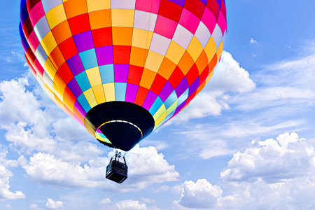 Colorful hot air balloon flying in the blue sky with white clouds