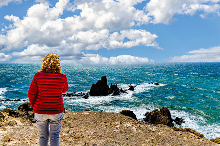 Blonde woman with curly hair looking at the horizon at the Las Sirenas reef in Cabo de Gata-Níjar, Almería, Spainの写真素材