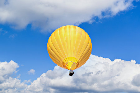 Hot air balloon flying in the blue sky with white clouds background.