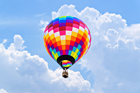 Colorful hot air balloon flying in the blue sky with white cloudsの写真素材
