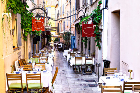 A typical street in Saint-Tropez, lined with tables and chairs from the local restaurants. French Riviera, Franceの写真素材