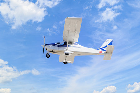 Single engine ultralight plane flying in the blue sky with white cloudsの写真素材