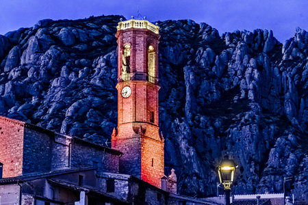 Views of the illuminated Church of Sant Corneli in Collbato, Barcelona at dusk, with the Montserrat mountain in the backgroundの写真素材