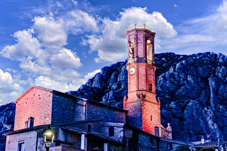 Views of the illuminated Church of Sant Corneli in Collbato, Barcelona at dusk, with the Montserrat mountain in the backgroundの写真素材