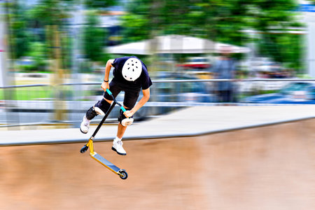 Young man practicing Scootering (Freestyle Scootering) in the SkatePark. blurred backgroundの写真素材