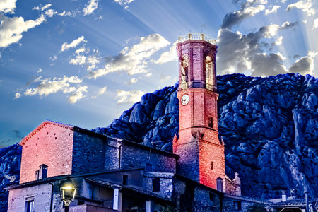 Views of the illuminated Church of Sant Corneli in Collbato, Barcelona at dusk, with the Montserrat mountain in the backgroundの写真素材