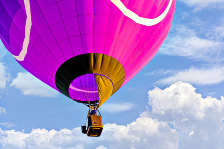 Colorful hot air balloon flying over blue sky with white cloudsの写真素材