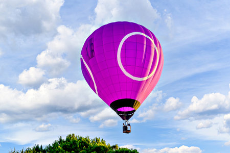 Colorful hot air balloon flying over blue sky with white cloudsの写真素材