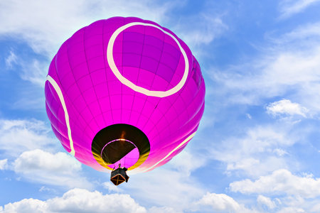 Colorful hot air balloon flying over blue sky with white cloudsの写真素材