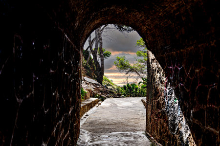 View from inside a tunnel to a green landscape with trees and blue sky.の写真素材