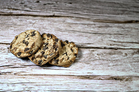 Three chocolate chip cookies isolated on rustic wooden table. Cookies.の写真素材