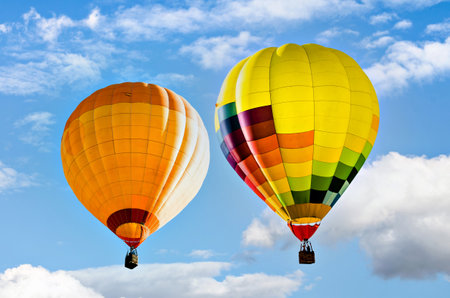 Colorful hot air balloon flying over blue sky with white cloudsの写真素材