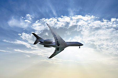 Private business plane flying under a blue sky with white clouds