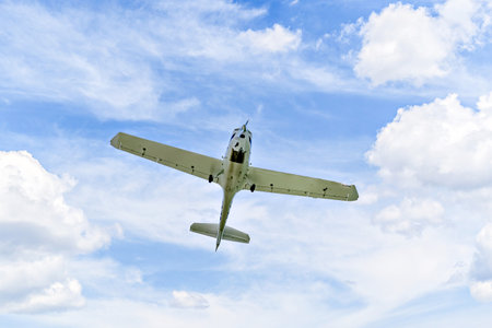 Single engine ultralight plane flying in the blue sky with white cloudsの写真素材