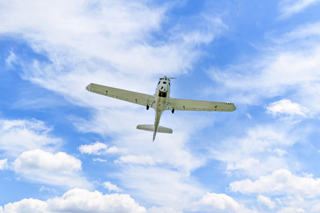 Single engine ultralight plane flying in the blue sky with white cloudsの写真素材