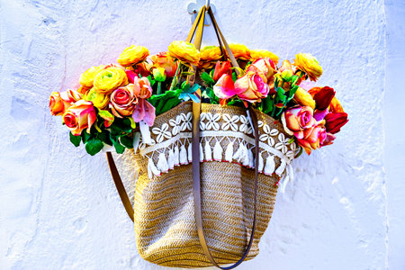 Floral arrangement in a straw bag hanging on the wallの写真素材