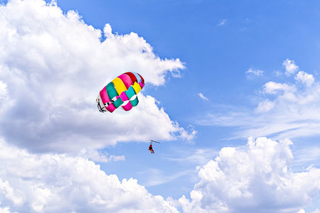 Two people parasailing under a colorful parachute in the sky