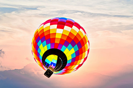 Colorful hot air balloon flying under orange sunset skyの写真素材
