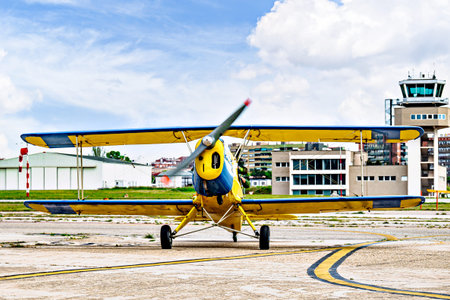 A yellow single-engine biplane waiting for takeoff at the airfield