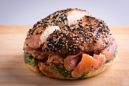 Bagel with salmon cut in half on wooden board, white backgroundの写真素材