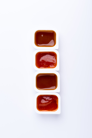 Four fast food dip sauces in plastic containers arranged as line isolated on white backgroundの写真素材