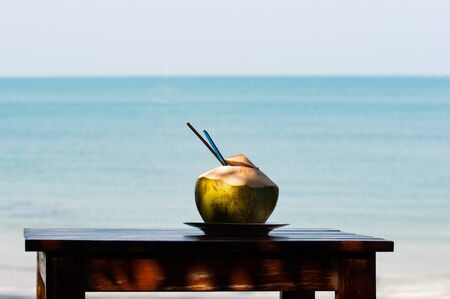 Coconut shake on wooden table with sea in backgroundの写真素材