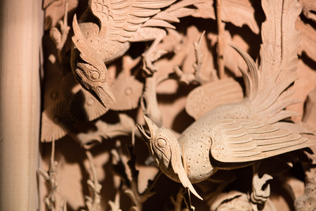 Traditional Chinese woodcarving of two birds fighting as decoration on a doorの写真素材