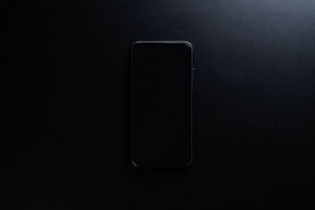 A Black smartphone isolated on black background.