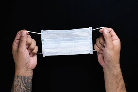 A man hand holdind a medical mask isolated on Black background.