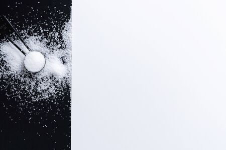 Black measuring spoons with salt on black and white background.の写真素材