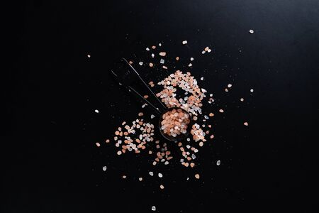 Black measuring spoons with Himalayan salt on black background.の写真素材