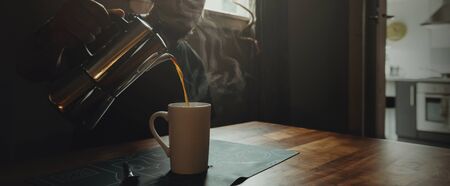 A man holding a moka pot and pouring coffee. close-up drip coffee isolated in dark space.の写真素材