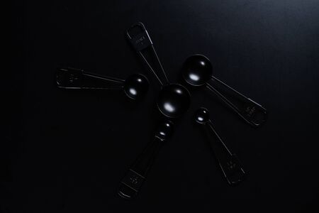 Black measuring spoons on black background.の写真素材