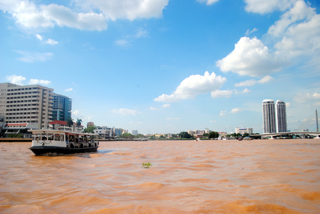Boat and brown river with blue sky at Chao Phra Ya river,Bangkok,Thailandの写真素材