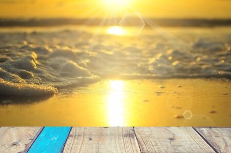 Blur smooth wave sunset beach with empty old wood table background.の写真素材