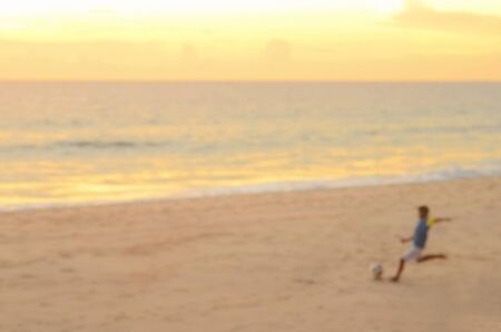Blur boys playing football on beach and twilight sky abstract background.の写真素材