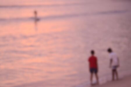 Blur children playing on tropical sunset beach abstract background.Sun light bokeh effect.の写真素材