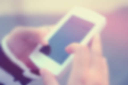 Blur woman hand using smart phone abstract background.Retro color style.の写真素材
