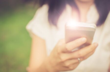 Blur woman using smart phone in park abstract background. Retro color style.の写真素材