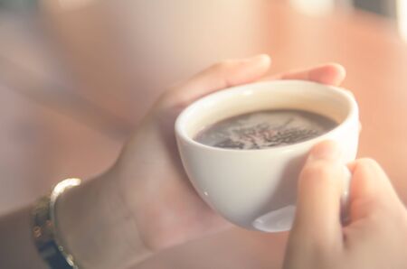 Blur woman holding a cup of coffee with sunlight abstract background.