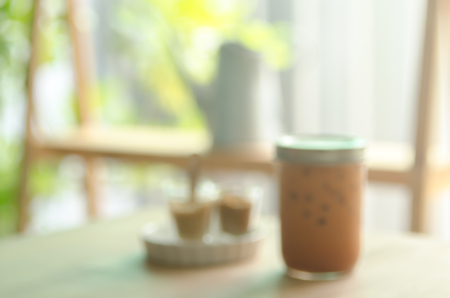 Blur ice milk tea on wood table in cafe abstract background.の写真素材