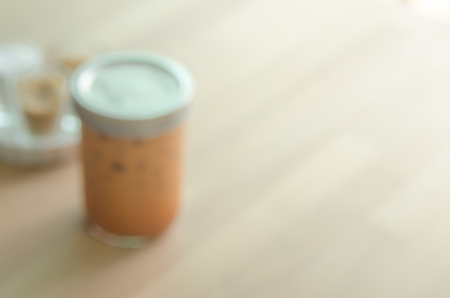 Blur ice milk tea on wood table in cafe abstract background.の写真素材