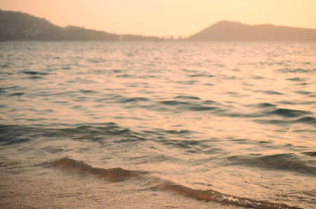 Blur tropical sunset beach with bokeh sun light wave abstract background. Travel concept. Retro color style.の写真素材