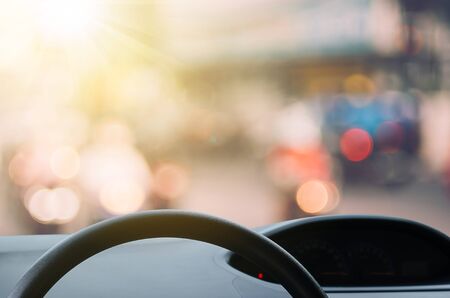 Inside car view ,steering wheel on blur traffic road with colorful bokeh light abstract background. Copy space of transportation and travel concept. Vintage tone filter color style.の写真素材