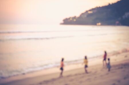 Blur kids playing on tropical sunset beach with bokeh sun light wave abstract background. Copy space of summer vacation and business travel concept. Vintage tone color style.の写真素材