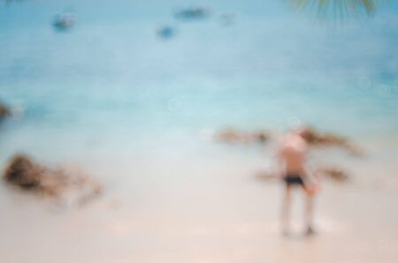 Blur man on tropical beach with bokeh sun light wave abstract background. Copy space of summer vacation and business travel concept. Vintage tone color filter style.の写真素材