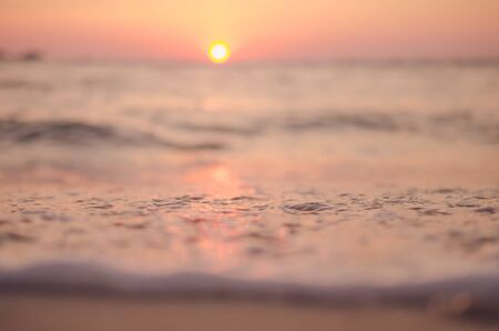 Blur tropical sunset beach with bokeh sun light wave abstract background. Copy space of summer vacation and business travel concept. Vintage tone color filter style.の写真素材