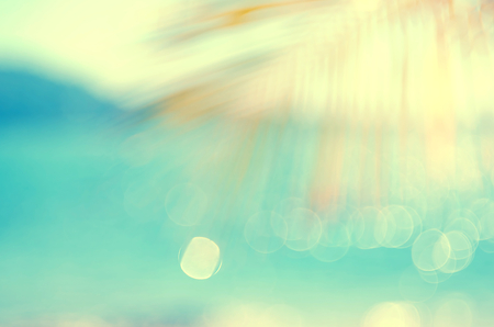 Blur beautiful nature green palm leaf on tropical beach with bokeh sun light wave abstract background. Copy space of summer vacation and business travel concept. Vintage tone filter color style.の写真素材