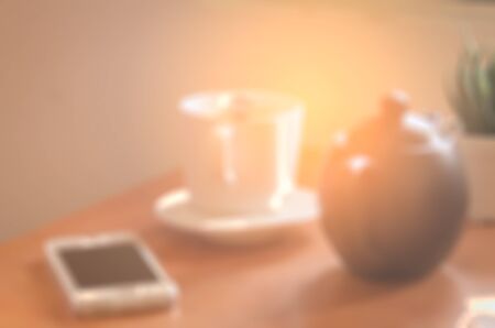 Blur cup of coffee and smart phone abstract background. Copy space of lifestyle and drink concept. Vintage tone filter color style.の写真素材