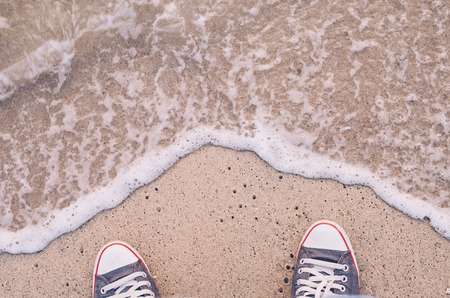 Top view of shoes on tropical wave beach, selfie, travel adventure concept.Retro tone filter color style.の写真素材
